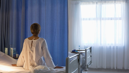 Woman in hospital gown sitting on hospital bed.jpg