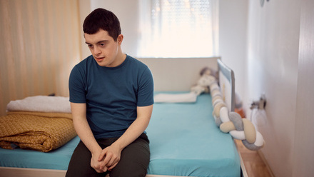 Young disabled man sitting on a bed.jpg