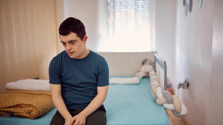 Young disabled man sitting on a bed.jpg