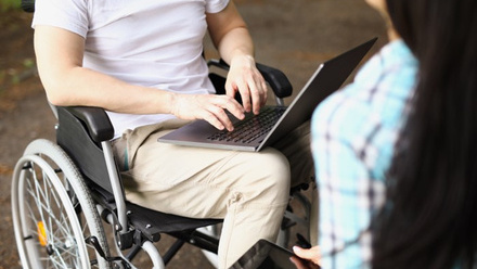 Man in wheelchair with laptop outdoors.jpg