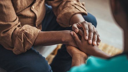 Two people sitting opposite holding each others hands.jpg